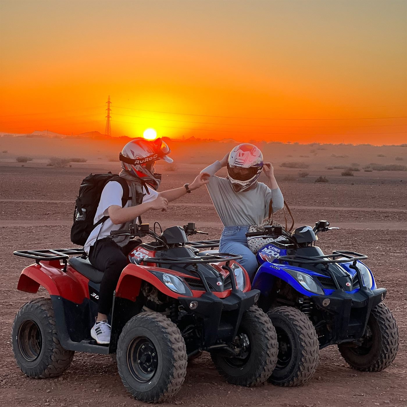 Two riders on quad bikes at sunset in the Marrakech desert